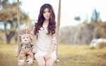 Asian girl sitting on a swing with a teddy bear Desktop wall